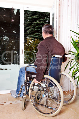 Mann sitzt im Rollstuhl und blickt aus dem Fenster