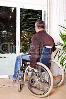 Mann sitzt im Rollstuhl und blickt aus dem Fenster