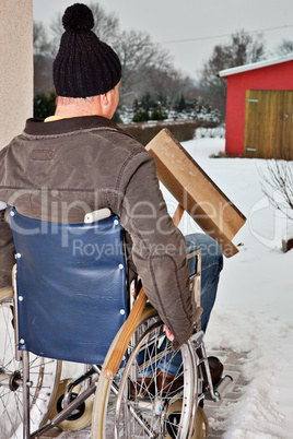 Mann im Rollstuhl beim Schnee schieben