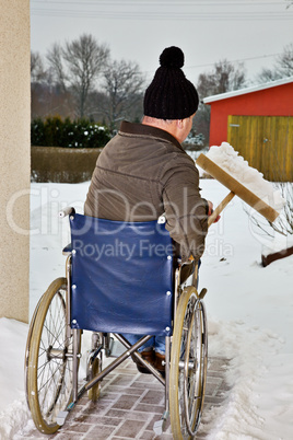 Mann im Rollstuhl beim Schnee schieben