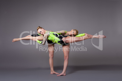 Two young woman as acrobats exercise pair program