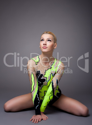 Young woman in gymnast suit posing on grey
