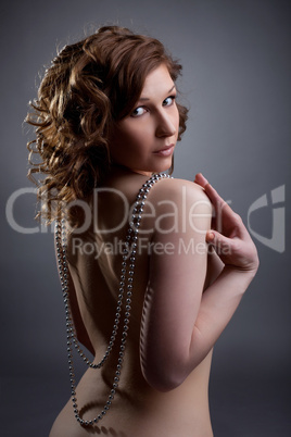 nude young woman posing with silver beads