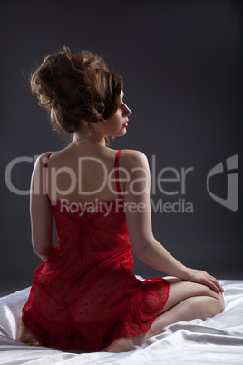 Sexy woman in red portrait on white silk bed