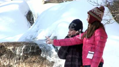 Teenage girls talking by water fall on winters day
