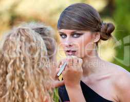 Makeup master applying lipstick with brush