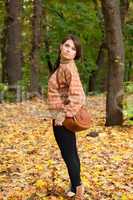 Young girl with handbag standing in the forest