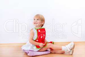 Cheerful little girl in red apron