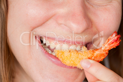 Pretty girl eating grilled shrimp