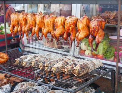 Row of grilled fish and hens on the street market