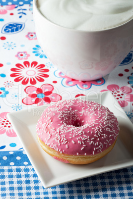 Rosa Donut und eine Tasse Cappuccino