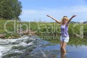 fröhliche Frau steht in einem Fluss