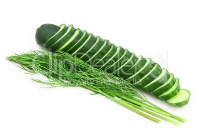 a cucumber with the cut half lying on a dill