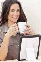 Woman Using Tablet Computer At Home Drinking Tea or Coffee