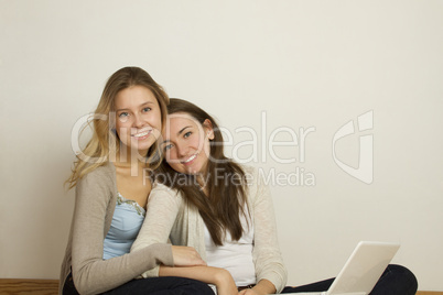 Two attractive friends at home with laptop