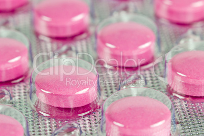 Closeup pink pills in transparent plastic package