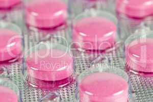 Closeup pink pills in transparent plastic package