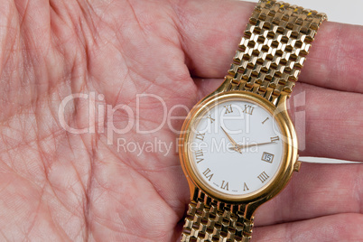 Gold watch with white face in palm of hand