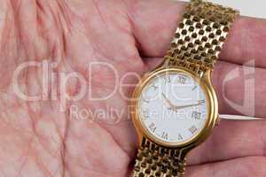 Gold watch with white face in palm of hand