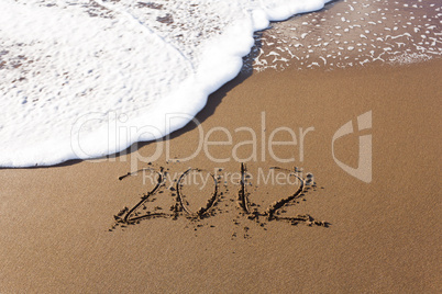 2012 written in sand with waves