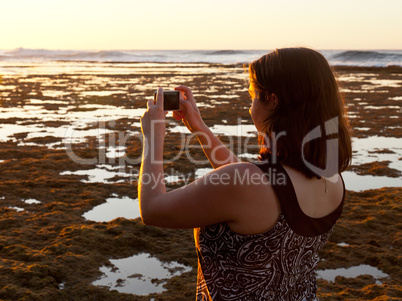 Girl taking photo of sunset on phone