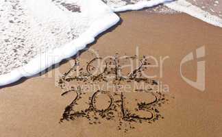 2012 and 2013 written in sand with waves