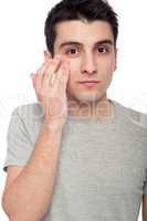 Young man applying eye cream