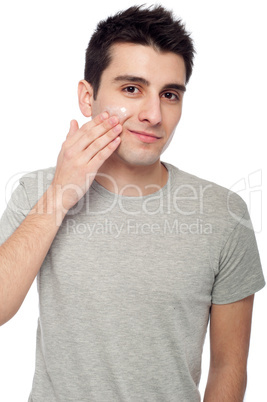 Young man applying cream lotion