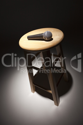 Microphone Laying on Wooden Stool Under Spotlight