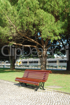 Wooden bench on a park and a train passing (behind)