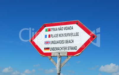 Sign at the beach (unguarded beach) against blue sky