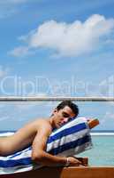 Young man sunbathing in a Maldives resort room