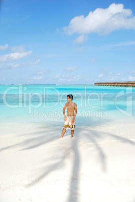 Young man standing on a tropical beach in Maldives