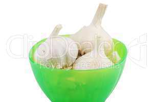 Green bowl of fresh garlic on white