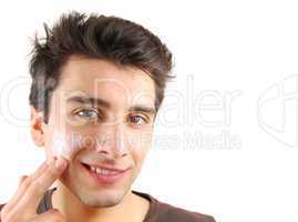 Smiling man applying face cream