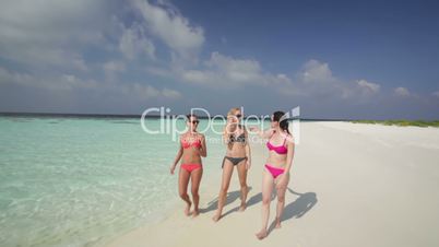 women in bikinis on sandy beach