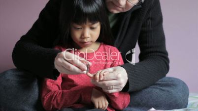 Girl Getting Her Fingernails Trimmed By Mother