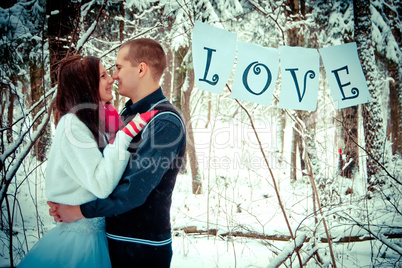 Couple kissing in the winter snow forest.