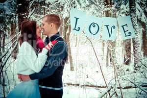 Couple kissing in the winter snow forest.