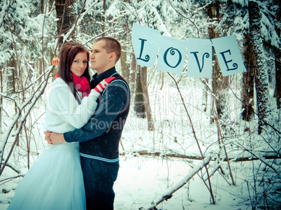 Couple in love hugging in the winter snow forest.