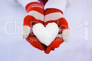 Red gloves hold white snow heart.