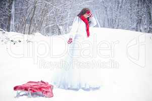 Beautiful girl pulling slides in snow forest.