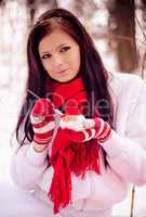 Young beautiful girl in snow forest painting heart.