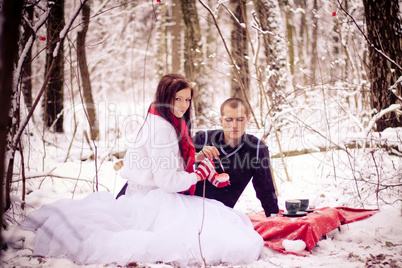 Couple in love in winter forest drinking tea.