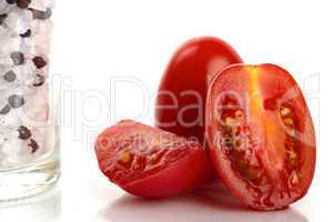 Frische Tomaten mit Salz- und Pfeffermühle als Nahaufnahme vor weißem Hintergrund