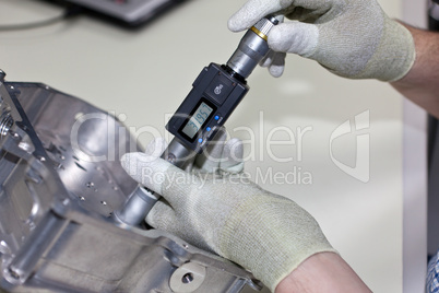 Mitarbeiter kontrolliert mit einer Innenmikrometerschraube die Bohrung in einem Getriebe Gehäuseteil