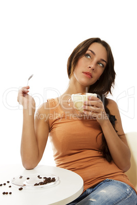 junge träumende frau mit einer tasse cappuccino kaffee sitzt an einem tisch