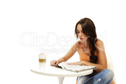 junge frau sitzt an einem tisch mit latte macchiato und liest zeitung