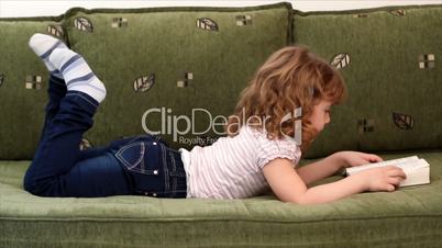happy little girl lying on bed and reading a book
