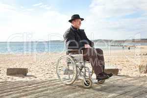Mann sitzt im Rollstuhl am Strand